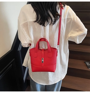 Dettaglio di una borsa a secchiello in pelle martellata rossa indossata a tracolla sul retro
