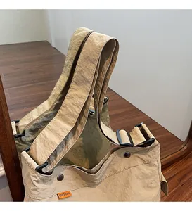 Dettaglio della tracolla larga regolabile kaki con fibbia nera su borsa in tela