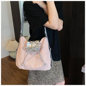 Detail of pink pleated fabric tote bag with silver metallic bow and contrast strap