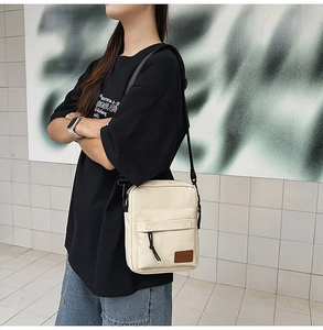 Detail of off-white canvas messenger bag with adjustable strap and designer logo patch