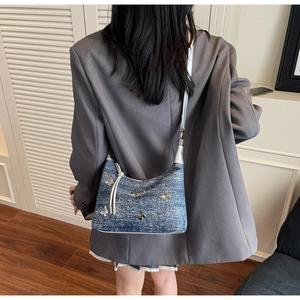 Detail der Jeans-Schultertasche mit silbernem 3D-Schmetterling und weißer Paspelierung