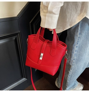 Detail of red pebbled leather handbag featuring silver metal clasp and sturdy handles