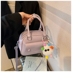 Lavender pillow handbag with cute plush monster charm shown in a daily travel setting