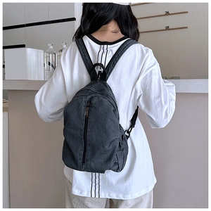 Vue arrière d'un grand sac à dos en denim gris porté par un modèle dans un studio