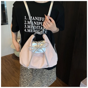 Pink drawstring tote with silver flap and bow detail shown on a model's shoulder