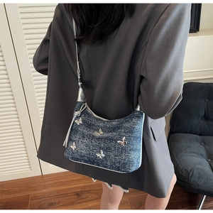 Détail du sac à épaule en denim bleu avec papillon argenté et strass scintillants
