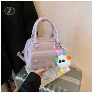 Close-up of lilac crossbody bag with smooth PU leather finish and colorful pompom charm