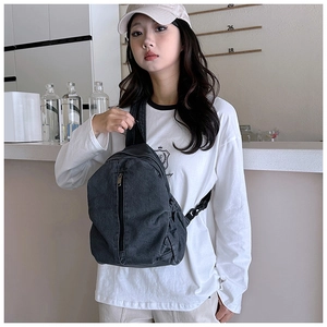 Détail du sac de poitrine en toile gris foncé avec fermeture éclair verticale et sangle
