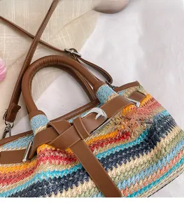 Detail of colorful striped straw tote bag with brown faux leather handles and silver hardware