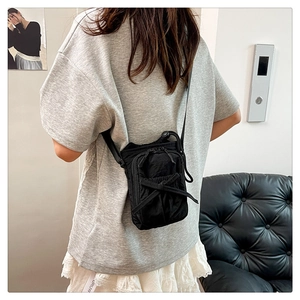 Detail of black nylon crossbody bag with bow tie decoration on model showing texture
