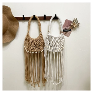 Detail of bohemian hand-woven bags with wooden beads and long fringe tassels in neutral tones