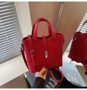 Detail view of red lychee pattern leather bucket bag with silver twist lock and strap