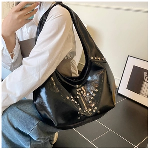 Detail of black Hobo bag with silver rivet star pattern shown on model's shoulder