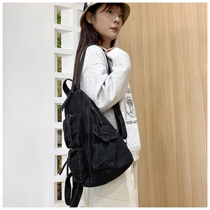 Detail eines schwarzen Canvas-Rucksacks mit Multi-Taschen-Design getragen von Model