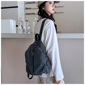 Détail du sac à dos en toile gris foncé avec fermeture éclair verticale au café