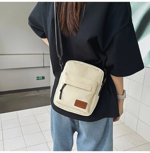 Minimalist cream canvas crossbody phone bag shown being worn with adjustable black strap