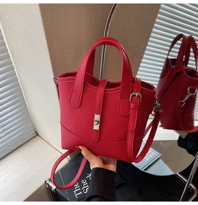 Detail of red lychee leather handbag showing silver twist lock and round top handles