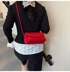 Gros plan du sac bandoulière rouge en cuir grainé avec rabat et fine sangle d'épaule