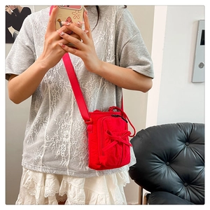 Mirror selfie showing the compact red bow crossbody bag worn by a young woman