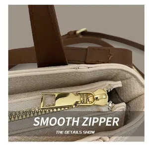 Detailed macro view of smooth gold metal zipper on cream white leather tote bag