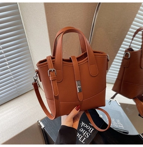Detailed shot of brown lychee leather tote bag with silver buckle and detachable strap