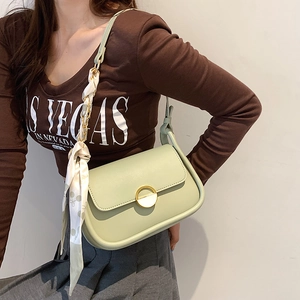 Détail du sac selle vert clair avec boucle dorée et accessoire foulard floral
