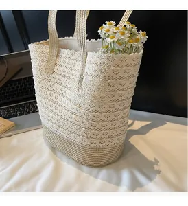 Détail d'un sac cabas en paille avec dentelle superposée et anses tressées dorées
