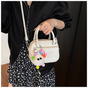 Detail shot of white glossy pillow bag featuring a large fuzzy monster charm and metal zipper