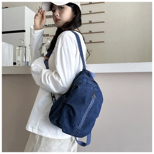 Détail d'un sac à dos en jean montrant la poche latérale zippée et la texture du tissu