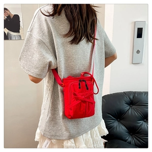 Red crossbody bag with bow detail and black zippers shown on person in casual setting