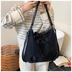 Macro view of black nylon tote bag with drawstring bow detail and leather handle