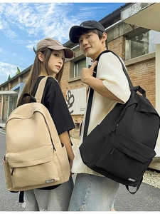 Minimalist nylon school backpack for students shown in khaki and black outdoor street view