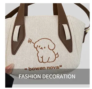 Close-up of cream canvas tote bag with brown cartoon dog embroidery and leather handle