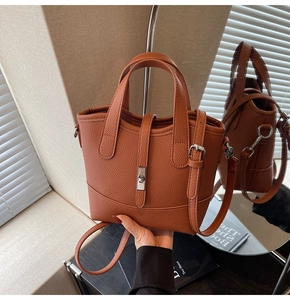 Detail of brown lychee grain leather tote with silver twist lock and adjustable strap