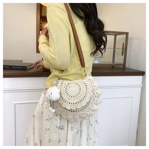Detail of white crochet saddle bag featuring scalloped edges and brown leather strap