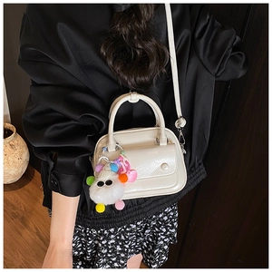 Detail of white PU leather pillow bag with fuzzy monster charm on model shoulder