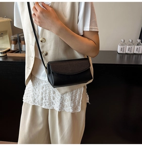 Gros plan d'un sac bandoulière en cuir noir grainé avec fermeture à rabat chic