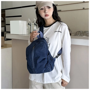 Gros plan sur un sac bandoulière en denim bleu foncé porté par un mannequin
