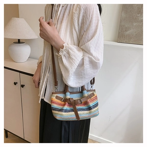 Detail of colorful woven straw crossbody bag with brown leather straps and metal buckle