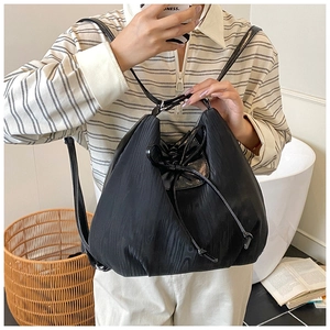 Detail of black drawstring bucket bag with unique pleated texture and thin leather straps