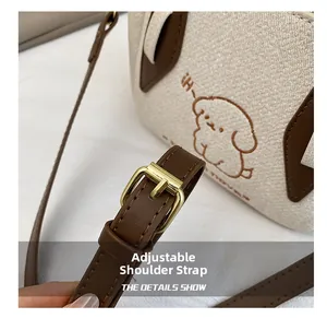 Detail view of the adjustable brown leather shoulder strap with a golden metal buckle