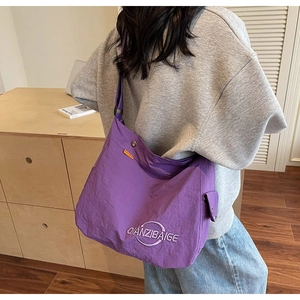Dettaglio borsa tote in tela viola con ricamo bianco e tracolla regolabile morbida