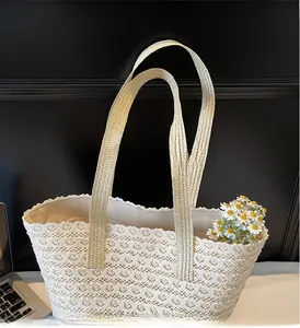 Détail du sac en paille tressée avec superposition de dentelle blanche et poignées