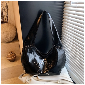 Detailed view of silver star rivet studs on a black patent leather hobo shoulder bag