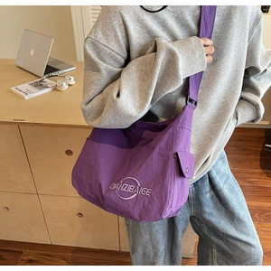 Vista dettagliata della borsa tote in nylon viola con ricamo bianco e tracolla regolabile
