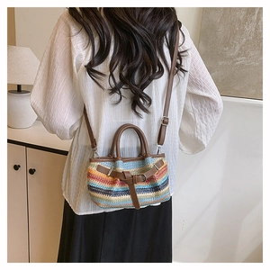 Close-up of colorful striped woven crossbody bag with brown faux leather handles and strap