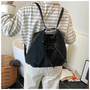 Detail of minimalist black nylon drawstring backpack shown from the back on model