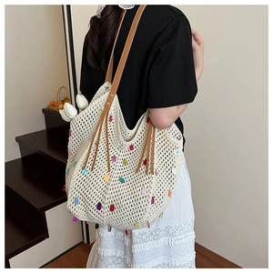 Detail of white crochet tote bag with colorful sequins and brown leather shoulder straps