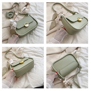 Détails d'un sac selle vert clair avec boucle dorée et accessoire ruban en soie floral