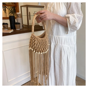 Detail of bohemian handmade woven bag with tassels, khaki cotton rope and wood beads